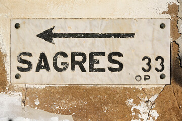 Direction to Sagres and distance information painted marble slab screwed to fortified historic wall...