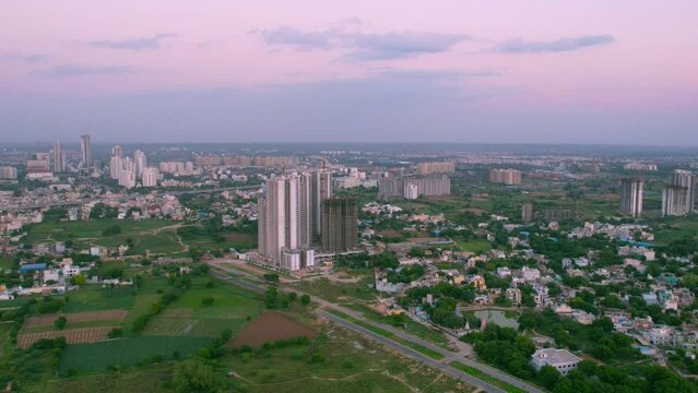 hyperlapse time lapse aerial drone shot of building under construction with crane on top with green feilds around on a cloudy day in gurgaon delhi India