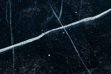 Cracked ice texture background. The textured cold frosty surface of the ice on black background.