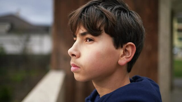 One pensive teenager boy standing outside. Closeup face of contemplative young male kid. Person looking at horizon