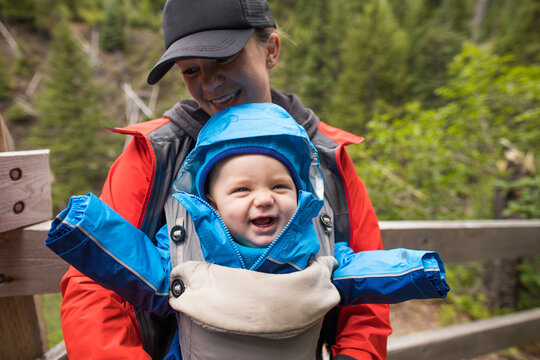 Mother carrying her happy daughter in baby carrier while hiking.