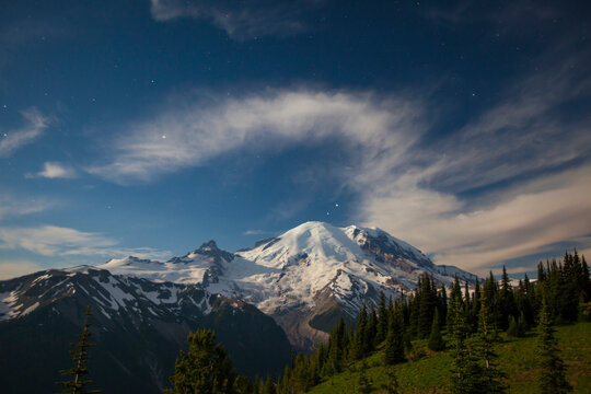 Stars and clouds fill the night sky over Mount Ranier.