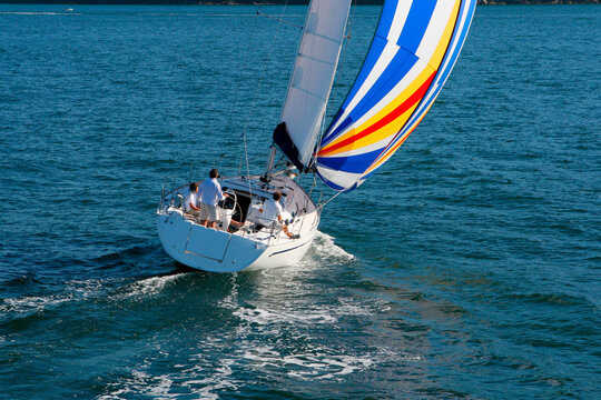Aerial view of a sailing yacht with a colorful spinnaker cruising in Pittwater on the North Shore from Sydney, Australia.