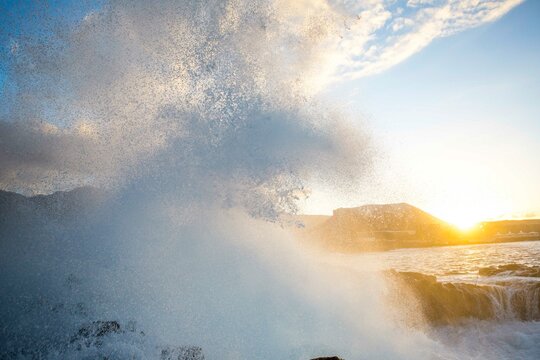 Wave exploding on the rocks at sunset