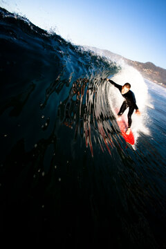 A male surfer pulls into a barrel at Zuma beach in Malibu, California.