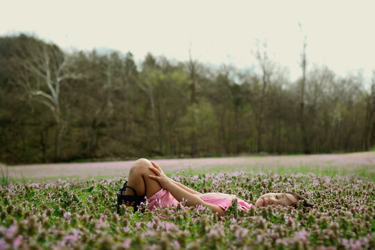 A girl rests in a field of flowers.