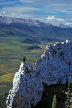 Young woman enjoys view from dolomite outcropping on Sapper Hill in the Northern Ogilvie Mountains, Yukon, Canada.