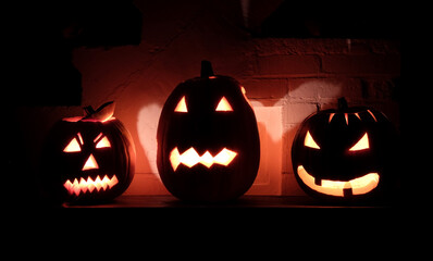 Drei ausgehöhlte Halloween-Kürbisse, die mit beängstigenden Fratzen leuchten