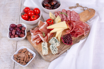 Italian antipasti wine snacks set. Cheese variety, Mediterranean olives, pickles, Prosciutto di Parma, pepper and salami. Charcuterie board.