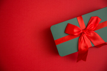 Grünes Geschenk mit roter Schleife auf rotem Hinergrund