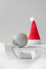Weihnachtlicher Hintergrund mit Platzhalter. Schlitten im Schnee mit silberner Weihnachtsbaumkugel
