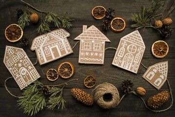 On a wooden background, a craft made of cardboard, a garland of paper houses on a jute rope next to...