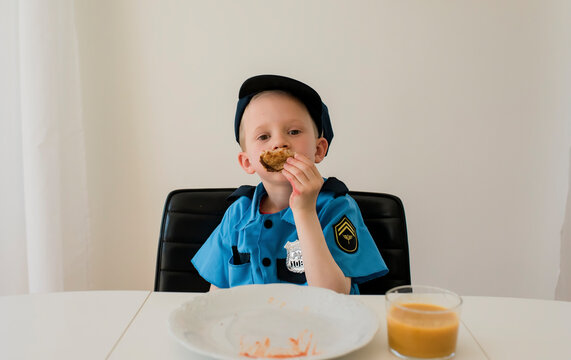 young boy in fancy dress at meal time playing with food