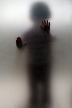 A Child Presses His Hands Against A Glass Door.