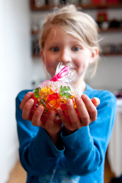 A Girl Longingly Eyes A Bag Of Gummy Bears