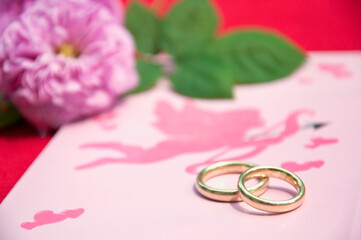 Wedding rings on wedding card with roses, close up