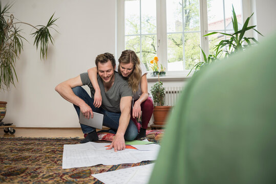 Couple looking at map in living room, Munich, Bavaria, Germany