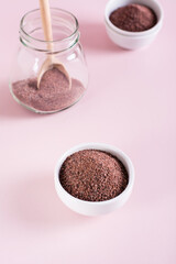 Black Himalayan rock salt kala namak in bowl on pink background. Vertical view