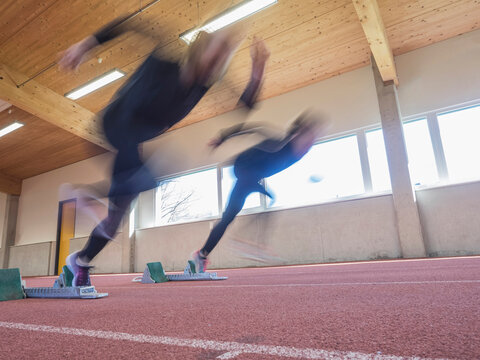 Two women runners in motion on tartan track, Offenburg, Baden-W&uuml;rttemberg, Germany
