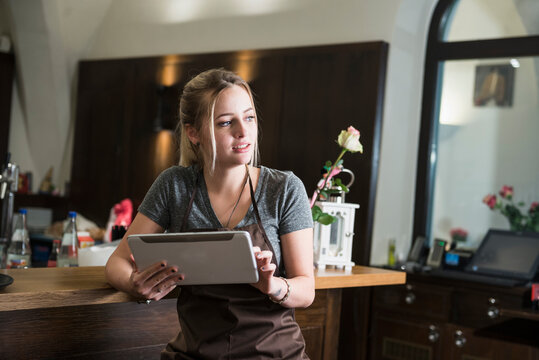 Young woman looking away while holding digital tablet at restaurant