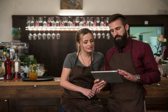 Confident restaurant owners discussing while using digital tablet