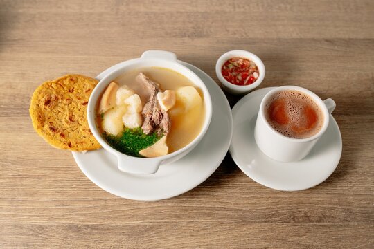 Bowl of colombian Caldo de costilla broth with beef ribs on a wooden table