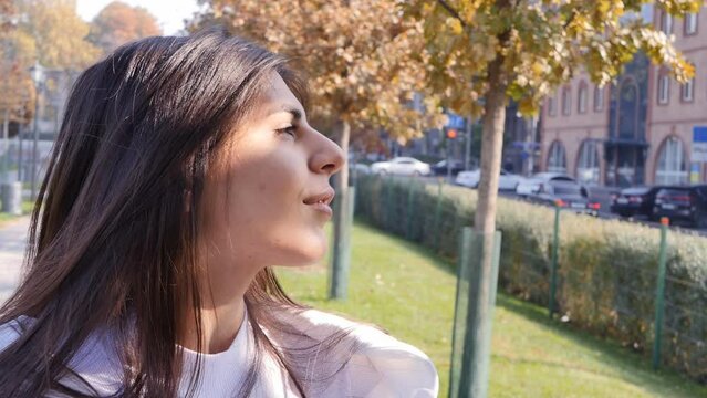 portrait: black-haired middle eastern beauty in the park on a sunny day in autumn looks at the sun and looks away. Cute and lovely young woman enjoying life outdoors
