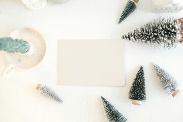 Christmas card mock up. Empty greeting card and little christmas trees decorations flat lay on...