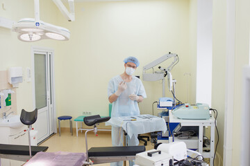 A male doctor taking a surgical instrument for a group of surgeons in the background in the surgery room. Steel medical instruments, ready to use. The concept of surgery and emergency care.