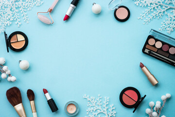 Winter cosmetic and christmas decorations on blue background. Flat lay image with copy space.