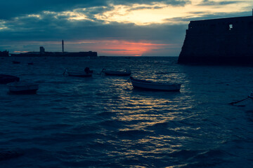 Sunset at La Caleta at low tide in Cadiz Spain with the castle of Santa Catalina on the right hand side