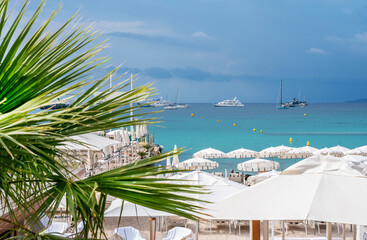 One of the private beaches on the Croisette with white beds (chaise lounges) and tents and  motion blurred people in Cannes,