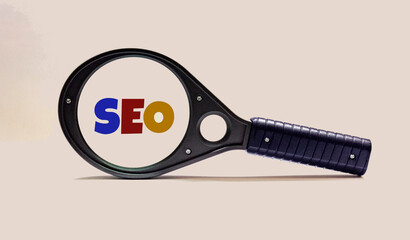 Selective focus of magnifying glass with SEO Search Engine Optimization text on white background.