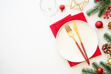 Christmas table setting with plate, cutlery and christmas decorations on white background. Flat lay image with copy space.