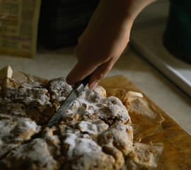 A woman's hand cuts a ready-made Charlotte apple pie into equal parts with a knife in the kitchen on a wooden board