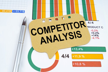 On the business charts is a pen and a sign with the inscription - Competitor Analysis
