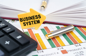 On the business charts there is a notepad, a pen and an arrow sticker with the inscription - Business System