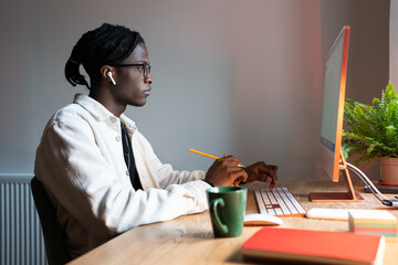 Progressive focused African American man designer working sits at computer studying customer...