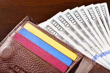 Close-up of a leather wallet with bank plastic cards and one hundred dollar bills. High angle view.