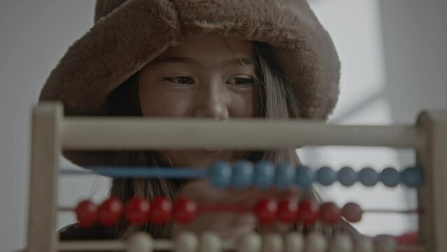 Young asian girl using an old wooden abacus and calculator doing mathematics
