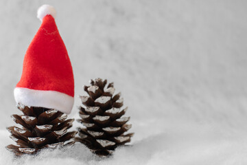 Weihnachtlicher Hintergrund mit Platzhalter. Tannenzapfen mit Nikolausmütze
