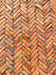 Red brick paving stones background. Road surface made of brown rectangular granite stones. Well maintained patterned pavement. Vertical frame.
