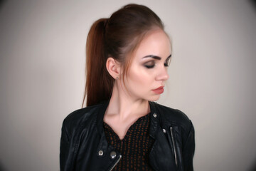 Portrait of a beautiful fashionable glamorous red-haired girl in the studio, in a leather jacket on...