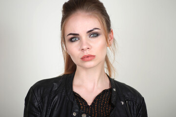 Portrait of a beautiful fashionable glamorous red-haired girl in the studio, in a leather jacket on...