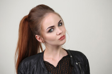 Portrait of a beautiful fashionable glamorous red-haired girl in the studio, in a leather jacket on...