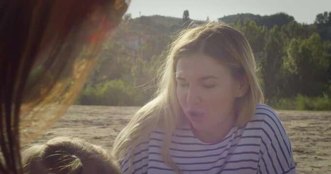 Woman friends having breakfast at summer beach party or picnic at sunset