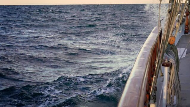 Sailing boat at sea. View from the deck of the yacht at the bow, closeup. Side view with green sea and waves. Baltic Sea with big waves. Slow motion. High quality FullHD footage