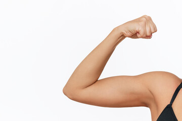 Cropped shot of young tanned strong fit woman raising arm and showing bicep on a white background....