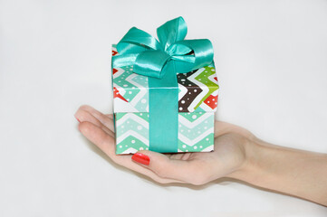 a box with a gift for a holiday or celebration in a female hand on an open palm on a white background. congratulations on the new year, christmas, birthday or other celebrations and memorable events
