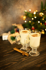 Two glasses of a traditional Christmas drink egg nog on wooden table